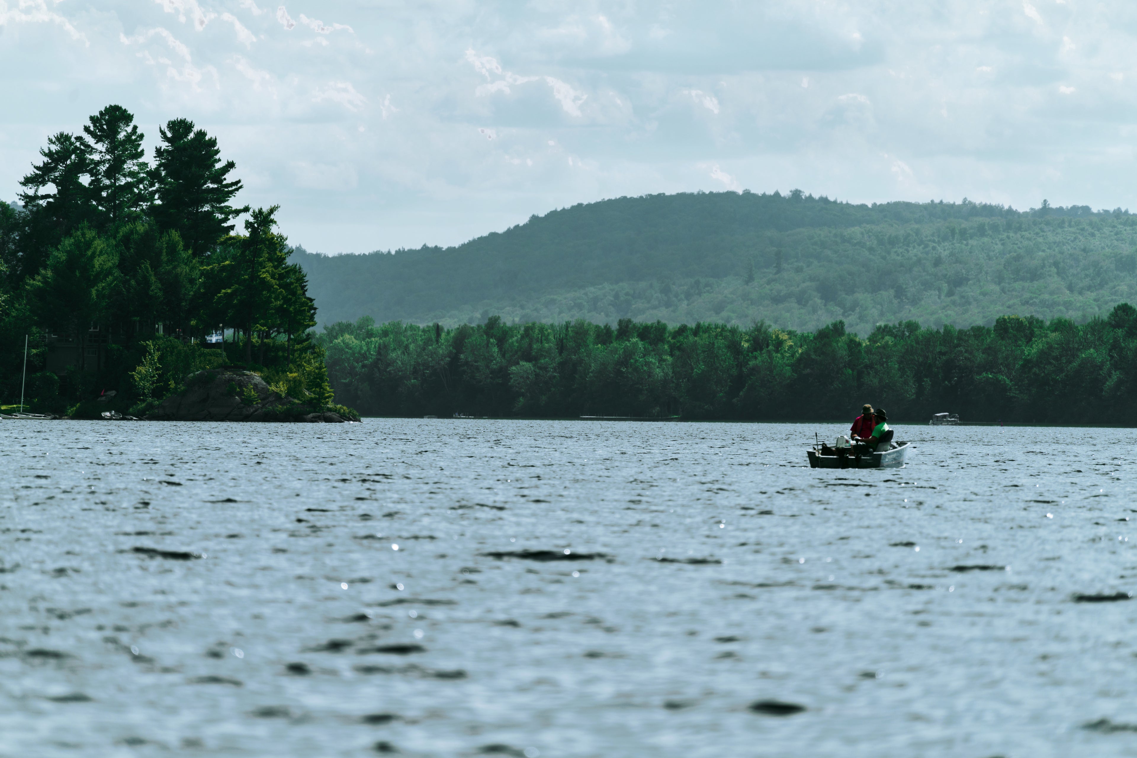 fishing boat on lake surrounded by woods